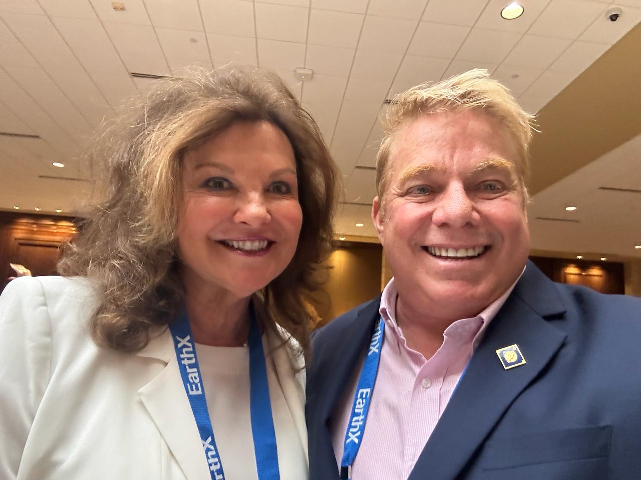 Two attendees with conference lanyards taking a smiling selfie.